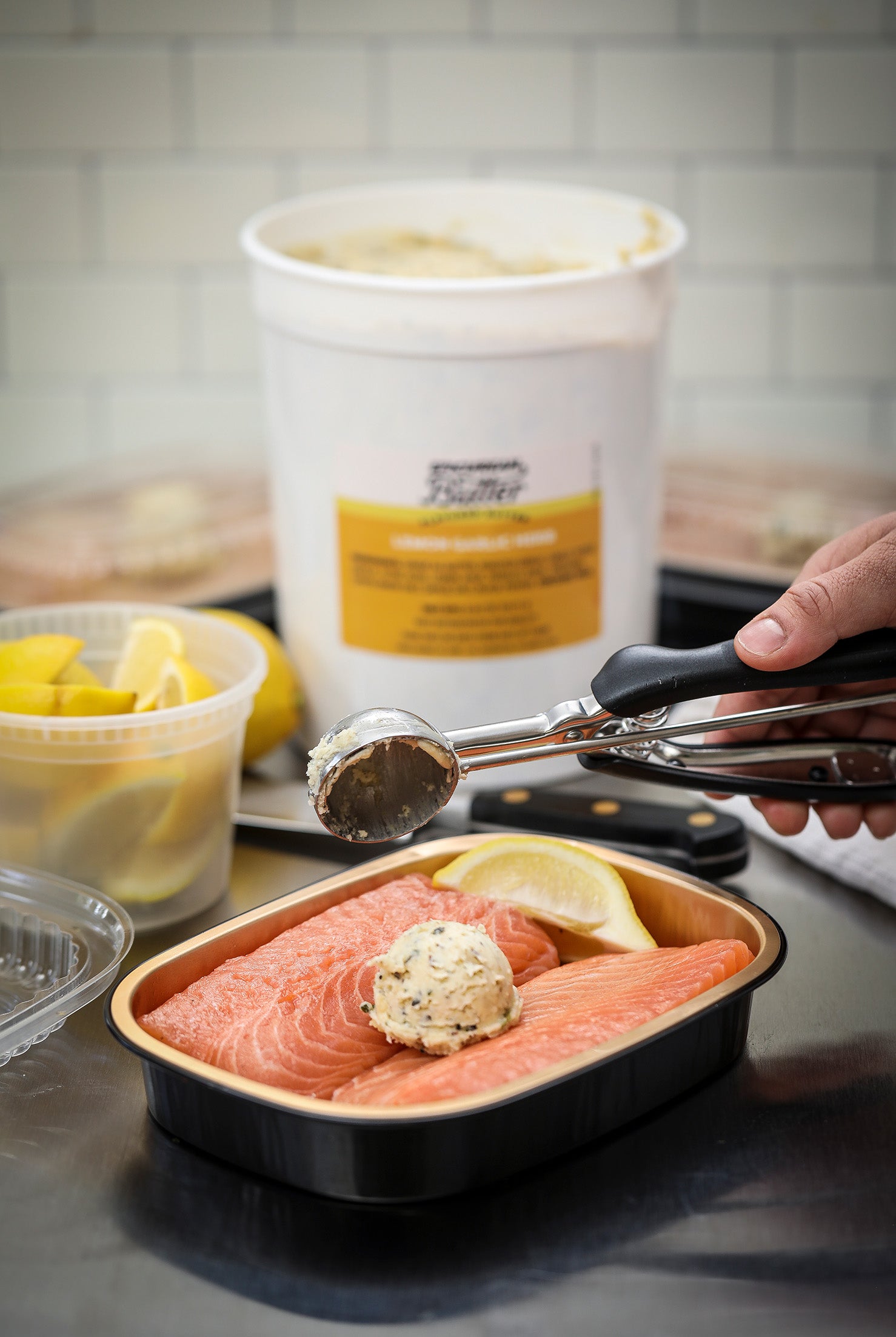 Adding scoop of Epicurean Butter from 5lb tub to ready-to-cook tray