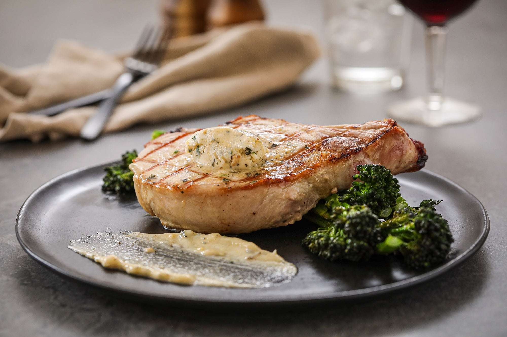 Pork chop plated dinner with Epicurean Butter Roasted Garlic Herb Flavored Butter