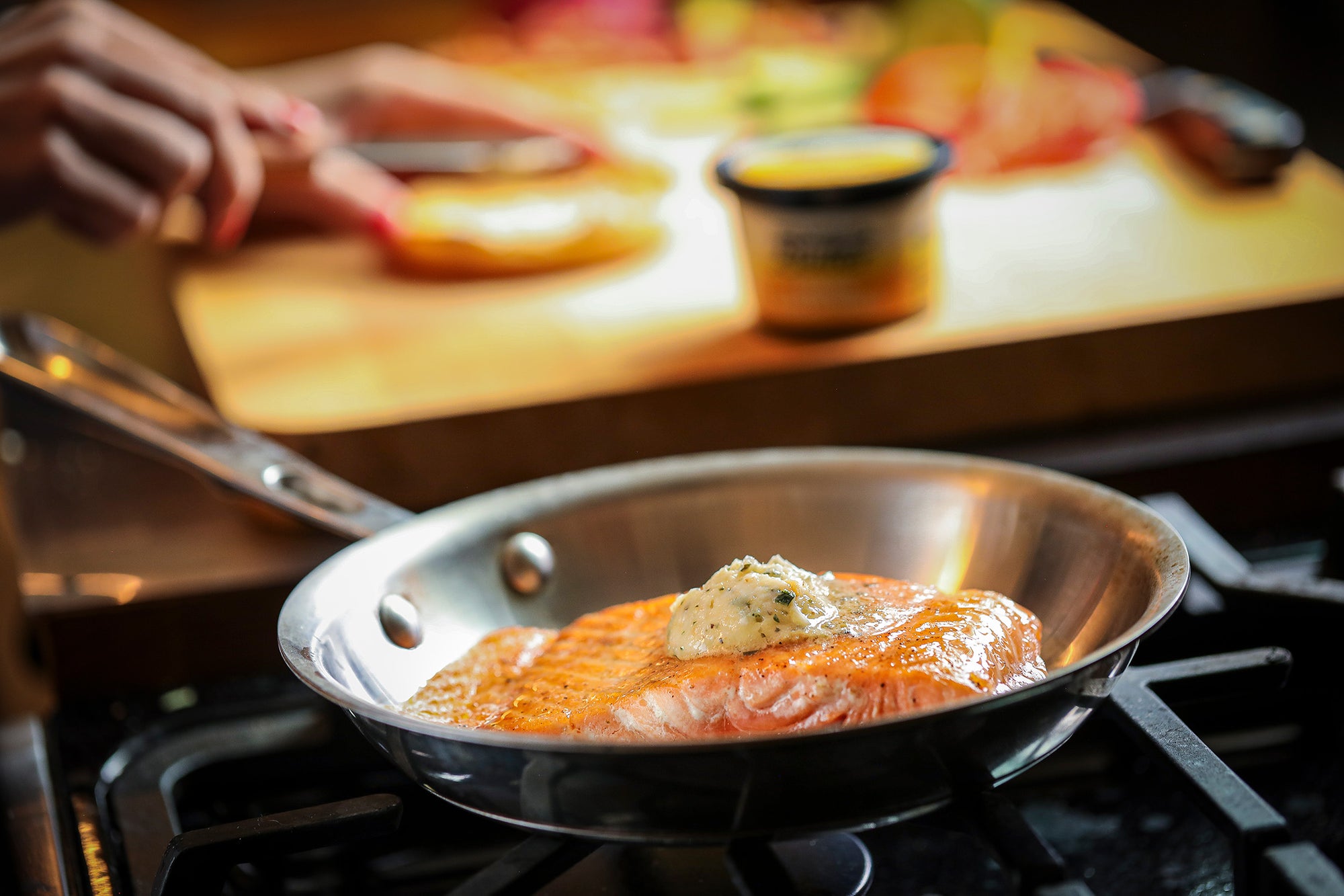 Salmon cooking in pan with Epicurean Butter Lemon Garlic Herb Flavored Butter