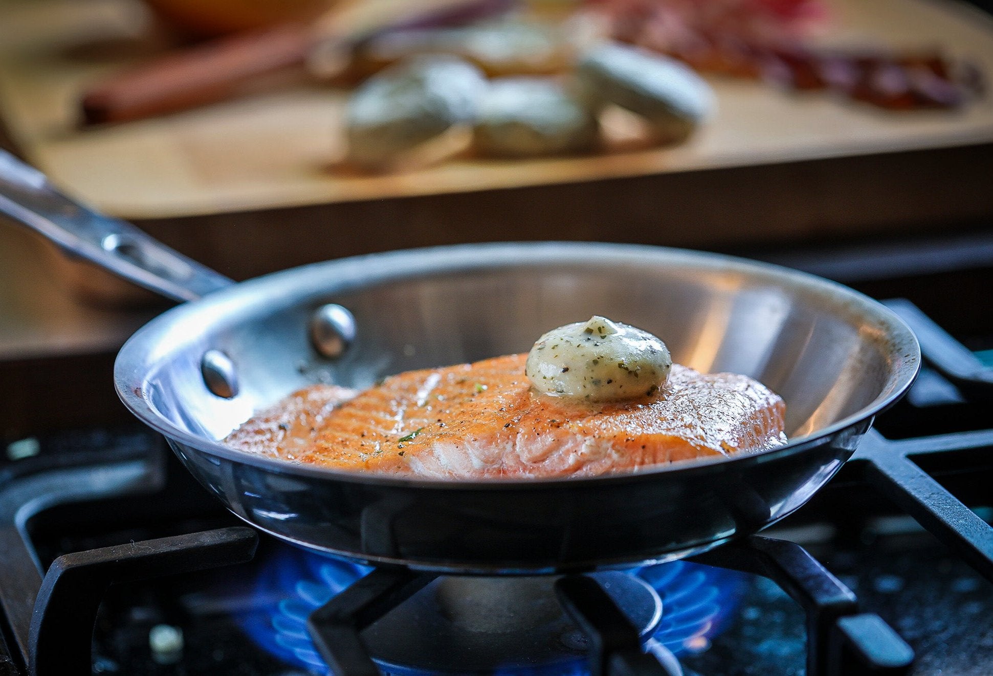 Salmon sizzling in pan with dollop of Epicurean Butter Lemon Garlic Herb Flavored Butter